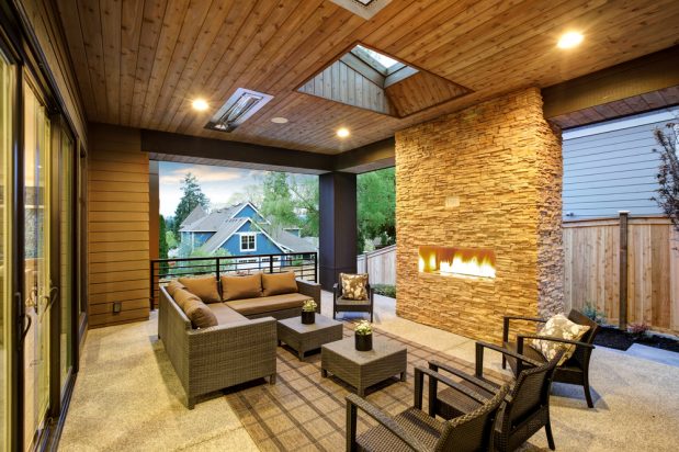 Outdoor covered patio with stone fireplace and furniture.