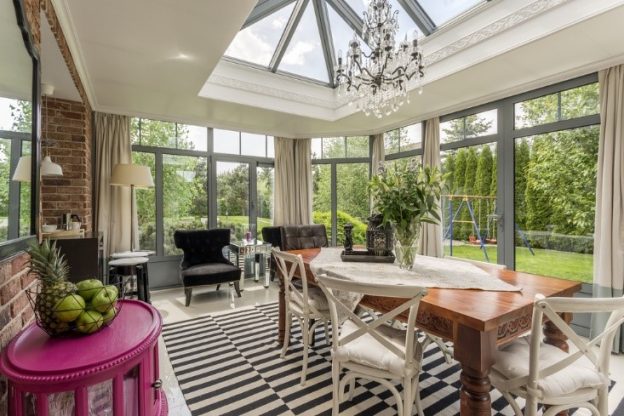 The inside of a sunroom with a table and chairs and a sky light.