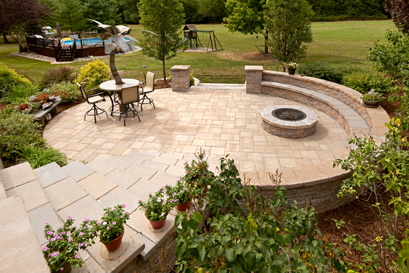 Round deck design with a firepit and greenery.