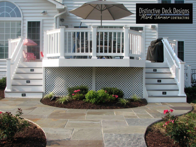A white, two story deck with stone pavers.