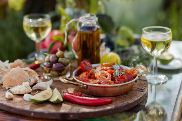 A close-up of a two-person, outdoor dinner with appetizers and wine glasses.