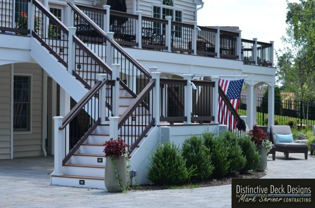 Two-story white deck with greenery.